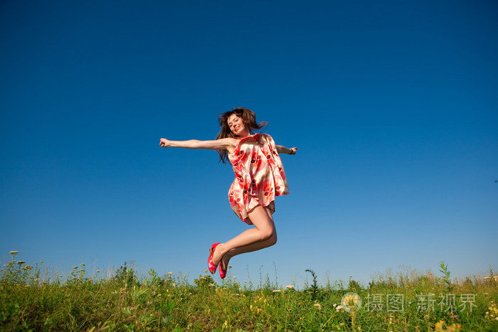快乐的年轻女子在田间跳跃