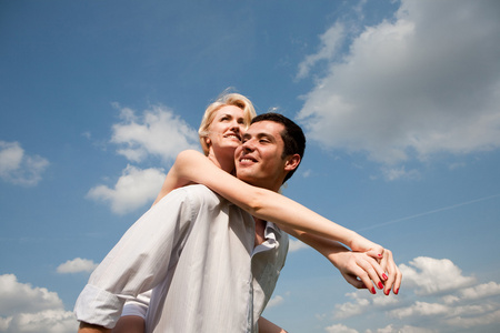 年轻的爱夫妇微笑在蓝蓝的天空下