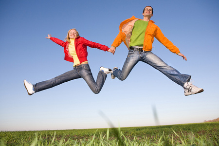 快乐的微笑夫妇在蓝蓝的天空中跳跃