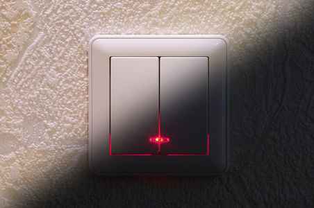 用于关闭水泥墙上的灯的白色开关按钮电灯开关在家里木墙背景灯开关