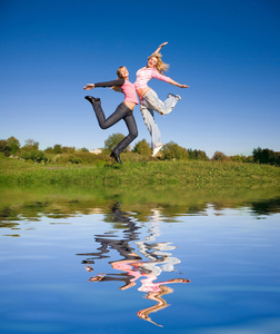 跳跃的绿草地上的两个快乐女孩