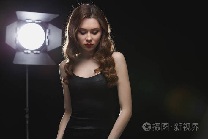年轻漂亮的女人站在聚光灯下工作室附近
