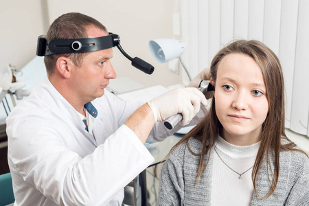 耳鼻喉医生看着病人耳朵用仪器。私人诊所。耳鼻喉科医生