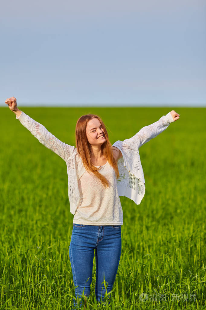 张开双臂在绿油油的麦田中的女孩