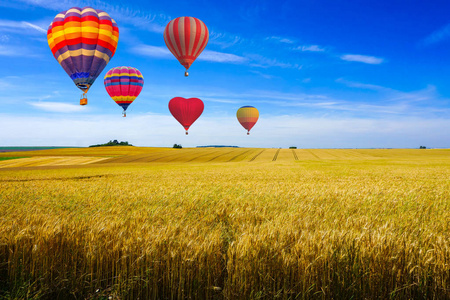 彩色热气球飞越收割的场和绿色山查看阳光明媚的日子，在夕阳的蒙塔涅德兰斯，法国