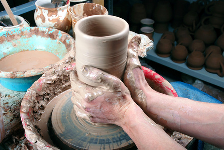 陶工的手在圆圈上制造一个土罐图片