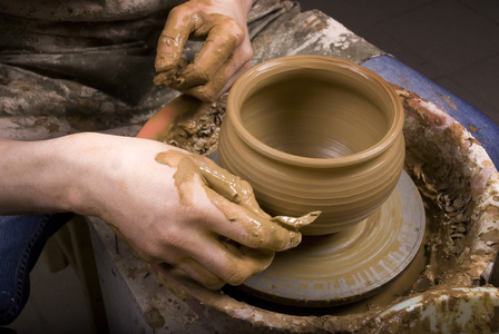 陶工的手在圆圈上制造一个土罐图片