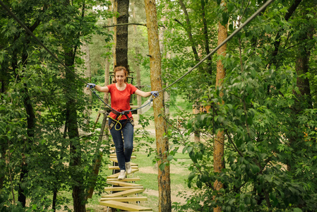 女人爬在森林冒险绳公园