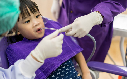 牙医和助理检查和清洗亚洲女孩牙齿我们