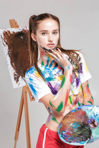 在五彩缤纷的颜料弄脏的女画家在画布上绘制