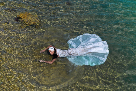 女人或在海水中的白色礼服的新娘的婚礼