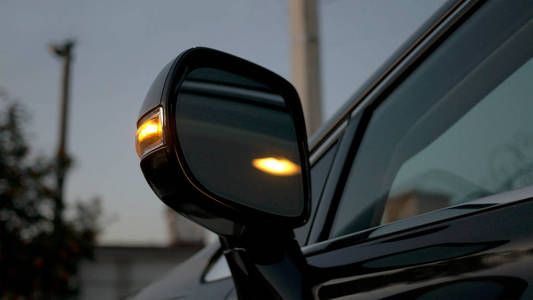 汽车后视镜。方向指示灯闪烁在晚上。现代汽车内饰