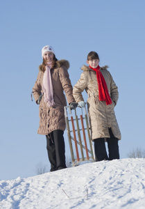 两个快乐的姐妹在冬天的时候雪橇