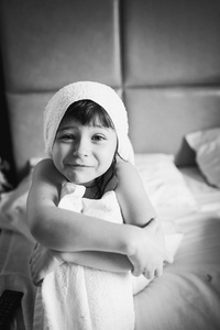 在洗完澡后坐在一张白色的床上一条毛巾洗的女孩