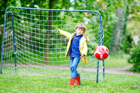 积极可爱小小孩男孩踢足球和足球和乐趣