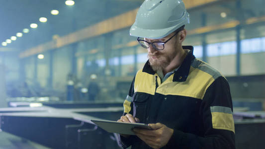 工程师在安全帽在重型工业中使用一台平板电脑