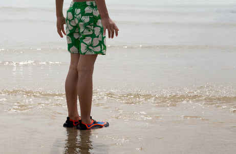 站在海边穿水鞋的小男孩