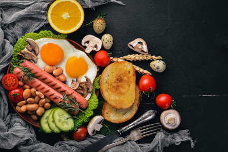 英式早餐。煎蛋, 香肠, 培根, 豆子, 土司, 西红柿, 咖啡杯在石桌上。文本空间的顶部视图