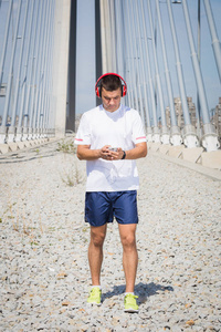 在桥上使用智能手机和耳机的慢跑