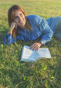 微笑的妇女读一本书在自然