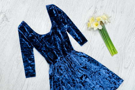 天鹅绒蓝色的连衣裙和一束水仙花。时尚理念