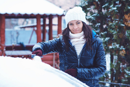 年轻漂亮的女性，在冬天的衣服从雪刷车中移除雪