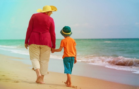 快乐祖母与孙子走在海滩