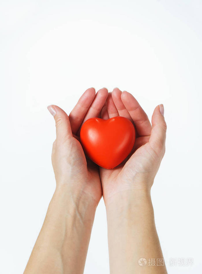 年轻的女孩在手心里有一颗象征红色的心.孤立