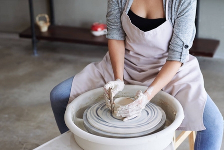 在车轮上制作陶瓷壶的年轻女子的裁剪图像