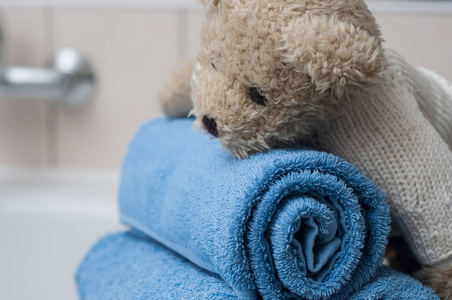 泰迪熊在浴室的卷蓝色浴巾