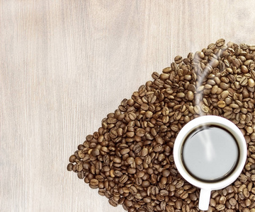 咖啡豆的心脏在木背景在一杯白色与咖啡的中心, 与它来蒸汽