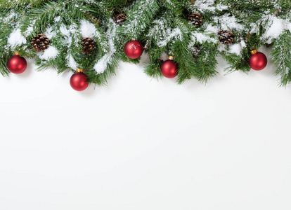 挂在冷杉树枝上的白雪皑皑的圣诞红色装饰品