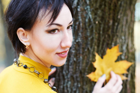 美丽的妇女画像以黄色叶子在树树皮背景, 秋天森林, 秋天季节