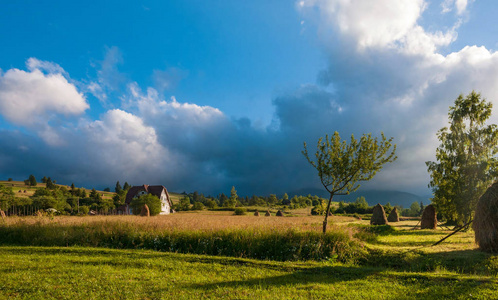 乡村景观与干草堆在夏天晴朗的一天。农村山风景用暴风云