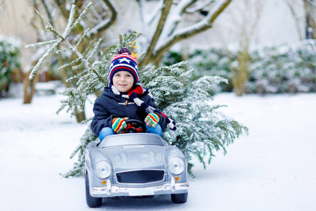 搞笑小微笑孩子男孩驾驶玩具车与圣诞树
