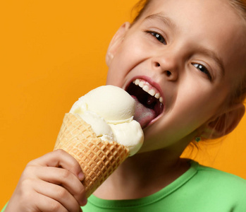 可爱的女孩孩子吃舔香草冰淇淋在华夫饼锥