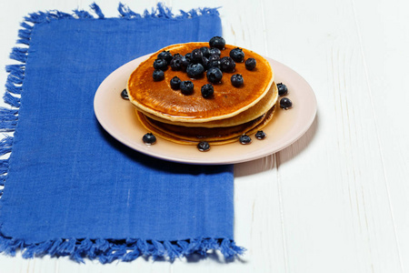 蓝色餐巾上有蜂蜜和蓝莓的薄饼