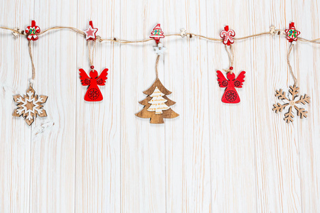 圣诞木制玩具挂在一个白色的木制背景的绳子上。美丽喜庆贺卡与自由空间