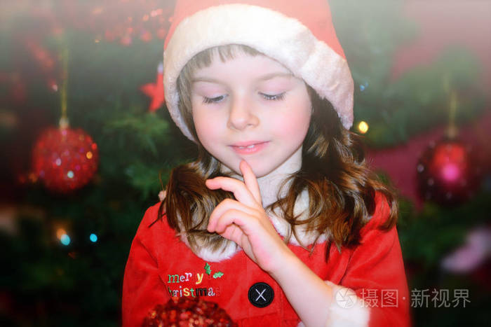 小女孩在圣诞老人的红色礼服许一个愿望