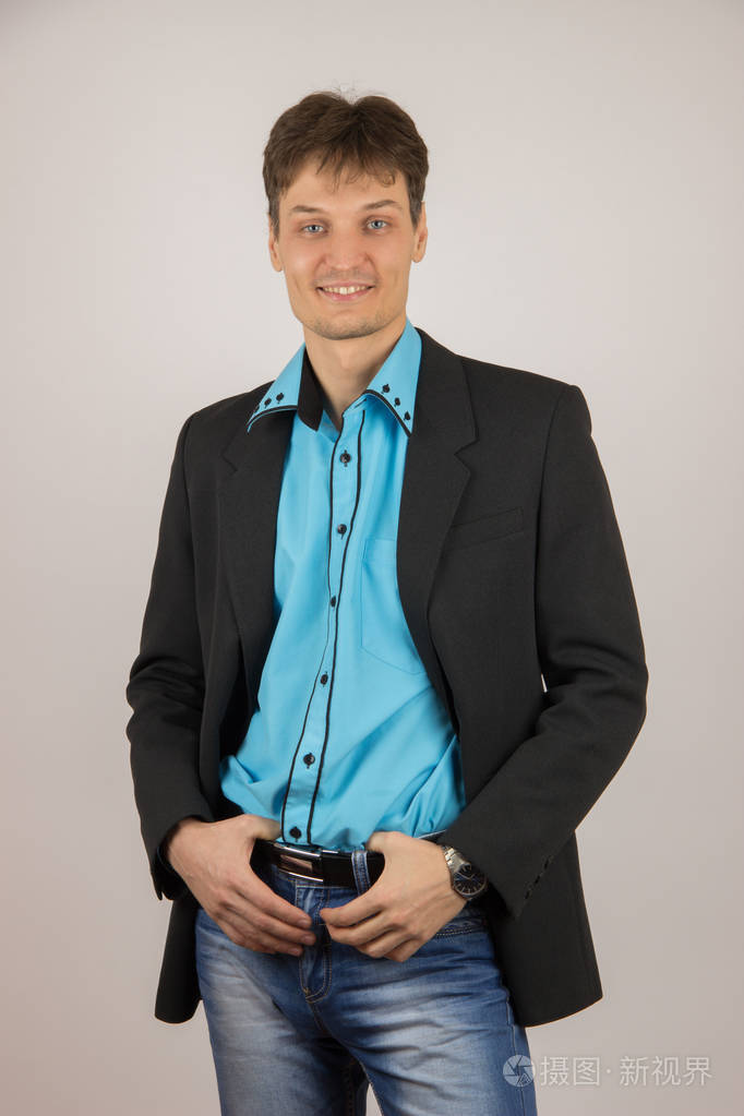 性感时尚的年轻小伙子,在蓝色的衬衫和牛仔裤,一件黑色外套