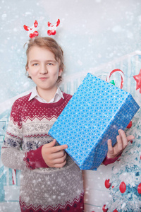 快乐的男孩穿着圣诞毛衣, 站在蓝色礼品盒