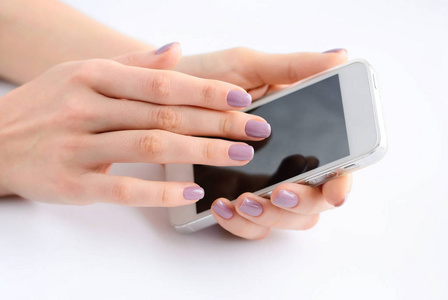 妇女的手里拿着手机，用手抚摸手机屏幕