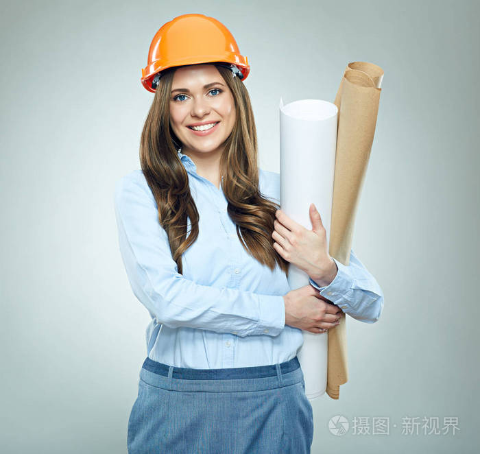 在橙色防护头盔和蓝色衬衣藏品纸计划的微笑的妇女工程师的画像