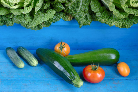 蔬菜.西红柿, 黄瓜, 西葫芦和卷心菜。有机食物在质朴的蓝色木背景