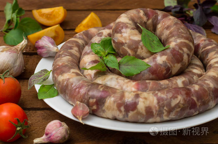 在木制背景的白色盘子里生鲜香肠.顶部视图.特写