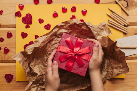 创意的人在一个用丝带绑着的漂亮的红色盒子里包着手工制作的礼物照片