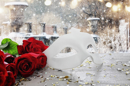 情人节浪漫的背景与美丽的玫瑰花束和化妆在木桌上的白色面具