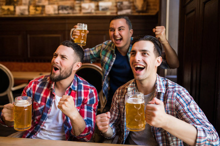 男球迷在电视上看足球, 喝啤酒。三其他人喝啤酒和愉快一起在酒吧