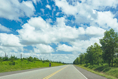 公路穿越森林和多云的丘陵背景