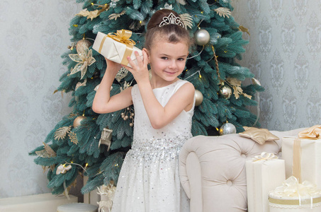 可爱的小女孩穿着白色礼服在圣诞前夜拿着礼物
